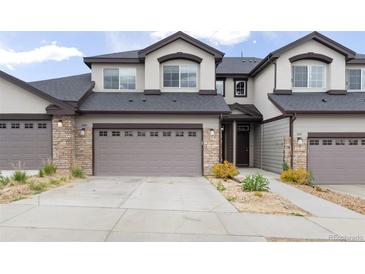 Inviting exterior of townhome with a two-car garage and stone accents at 1849 S Helena St, Aurora, CO 80017