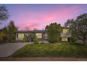 Charming home featuring well-manicured lawn, mature trees, solar panels, and brick accents under a vivid pink sunset at 13661 W Tufts Ave, Morrison, CO 80465