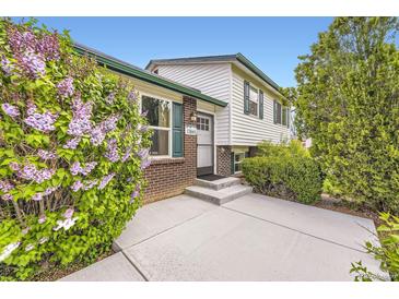 Charming home featuring brick accents, white siding, green trim, and a well-maintained front yard at 13661 W Tufts Ave, Morrison, CO 80465