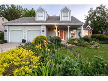 Charming home featuring colorful flower beds, a covered porch, and a two-car garage, creating an inviting curb appeal at 7189 S Kline St, Littleton, CO 80127