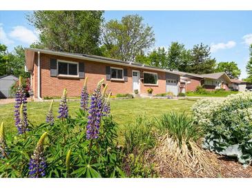 Charming brick home featuring a well-manicured lawn and vibrant flower beds at 6314 Brooks Dr, Arvada, CO 80004