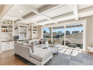 Spacious living room with large windows, coffered ceilings, built-in shelving, and access to an outdoor patio at 5880 Beeler Ct, Denver, CO 80238