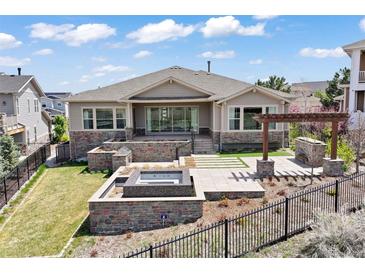 Beautifully landscaped backyard with stone patio, fire pit, and pergola, perfect for outdoor entertaining at 27381 E Lakeview Dr, Aurora, CO 80016