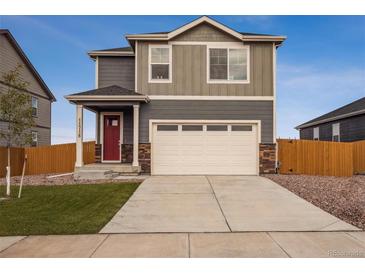 Charming two-story home with a two-car garage, red door, and well-maintained lawn at 816 Leeward St, Lochbuie, CO 80603