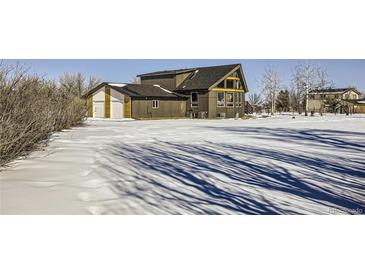 A remodeled home with a large backyard, snow-covered lawn, and attached garage at 4022 Arleigh Dr, Berthoud, CO 80513
