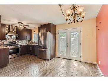 This spacious kitchen features stainless steel appliances, dark cabinetry and an adjacent dining area at 3659 W Union Ave, Denver, CO 80236