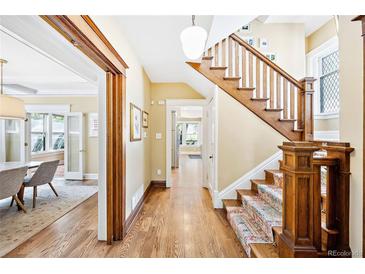 Hallway with hardwood floors and wooden staircase featuring a colorful runner, connecting different areas of the home at 677 N Gilpin St, Denver, CO 80218