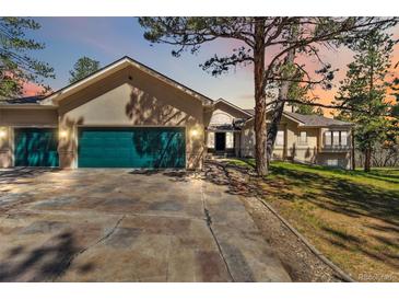 Stunning home featuring a green garage door, stone driveway, and mature trees at 1653 Gore Dr, Larkspur, CO 80118