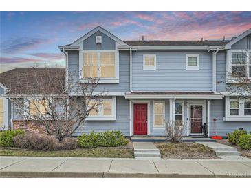 Charming townhome with a red front door, light blue siding, and manicured landscaping at 19046 E 57Th Pl # B, Denver, CO 80249