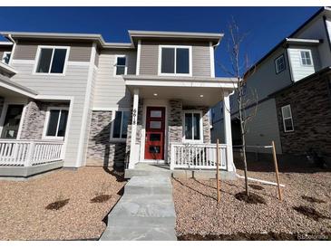 Charming townhome featuring stone accents, a red front door, and a cozy porch perfect for enjoying the neighborhood views at 6618 N Nepal Ct, Aurora, CO 80019