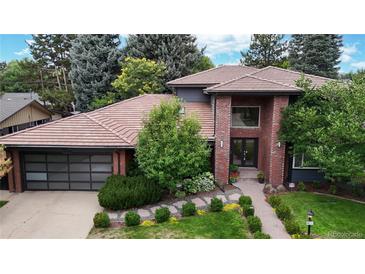Stunning brick home with a tile roof, lush landscaping, and a modern garage door at 463 Locust St, Denver, CO 80220