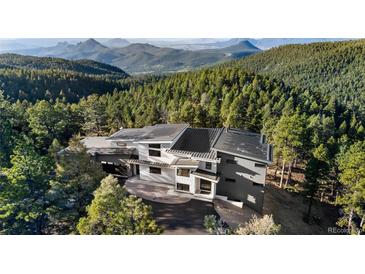 Stunning modern home nestled amongst a lush green forest with breathtaking mountain views in the distance at 13415 S Resort Dr, Conifer, CO 80433