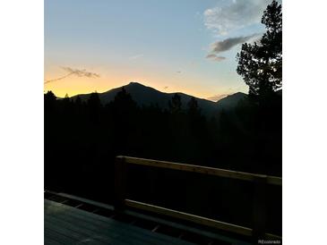 Breathtaking mountain sunset view from deck with silhouetted trees and fading sky at 33884 Bergen View Trl, Evergreen, CO 80439