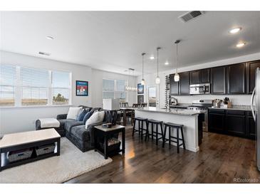 Bright, open-concept living room and kitchen with hardwood floors, granite countertops, and stainless steel appliances at 4680 Copeland Loop # 204, Highlands Ranch, CO 80126