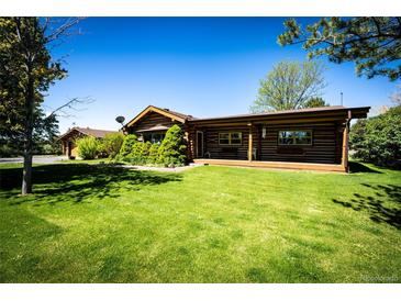 Charming log home with lush green lawn and mature landscaping creates a welcoming exterior at 2965 Wagner St, Strasburg, CO 80136