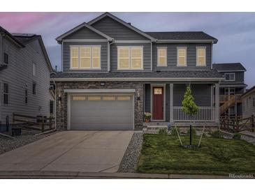 Charming two-story home featuring a gray exterior, stone accents, a two-car garage, and a cozy front porch at 1373 E Witherspoon Dr, Elizabeth, CO 80107