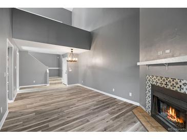 Bright living room features a cozy fireplace and wood plank flooring at 11103 E Alameda Ave # 201, Aurora, CO 80012