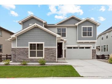 Beautiful two-story home with stone accents, gray siding, well-manicured lawn, and attached two car garage at 6263 E 142Nd Pl, Thornton, CO 80602