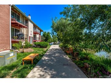 Apartment building with balconies and landscaped walkway with benches, creating a serene outdoor space at 12156 Melody Dr # 201, Westminster, CO 80234