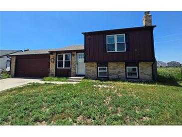Charming home with a brick and wood exterior, complemented by a well-manicured front yard and an attached two car garage at 275 Mckinley Dr, Bennett, CO 80102