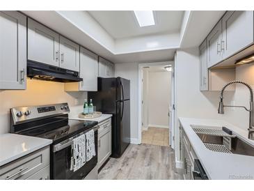 Well-lit kitchen with stainless steel appliances, gray cabinets, and a convenient doorway to another room at 3550 S Harlan St # 177, Denver, CO 80235