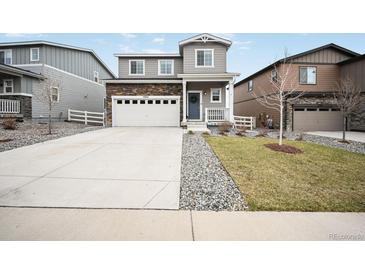 Charming two-story home featuring stone accents, a well-manicured lawn, and a spacious driveway at 5354 Blue Lunar Ln, Castle Rock, CO 80104