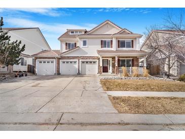 Charming two-story home with a three-car garage, a well-kept lawn, and a welcoming front porch at 11885 Helena St, Commerce City, CO 80022