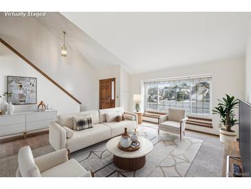 Bright living room featuring a large window, neutral decor, and a staircase at 2043 E Nichols Dr, Centennial, CO 80122