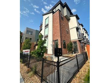Modern townhome featuring brick accents, black metal railings and a manicured front yard at 5423 S Prince St # B, Littleton, CO 80120