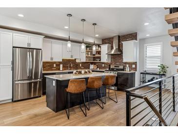 Modern kitchen features stainless steel appliances, brick backsplash, and a center island with bar stool seating at 5423 S Prince St # B, Littleton, CO 80120
