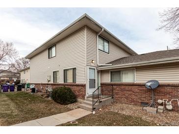 Tan two-story condo building with brick base and landscaping at 9255 E Lehigh Ave # 211, Denver, CO 80237