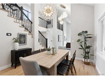 Bright dining room featuring hardwood floors, modern chandelier, and staircase with black metal railings at 4505 S Yosemite St # 362, Denver, CO 80237