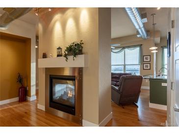 Open living room with a fireplace and hardwood floors at 10111 Inverness Main St # 425, Englewood, CO 80112