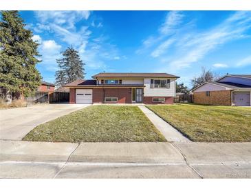 Charming split-level home with brick accents, a well-manicured lawn, and an expansive driveway at 4642 Everett Ct, Wheat Ridge, CO 80033