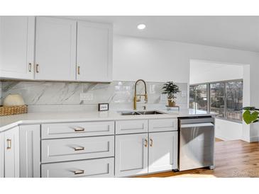 Bright kitchen features white cabinets, stainless steel appliances, and stylish countertops and backsplash at 4642 Everett Ct, Wheat Ridge, CO 80033