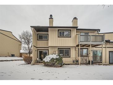 Back exterior view of a two-story townhouse with a balcony and snow-covered yard at 11919 E Yale Ave, Aurora, CO 80014