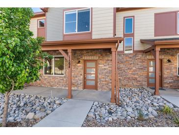 Charming townhome with a stone facade, covered entrance, and decorative rock landscaping at 11294 Bella Vita Dr, Broomfield, CO 80020