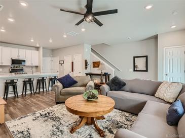 Cozy living room featuring hardwood floors, a ceiling fan, and comfortable seating at 11294 Bella Vita Dr, Broomfield, CO 80020