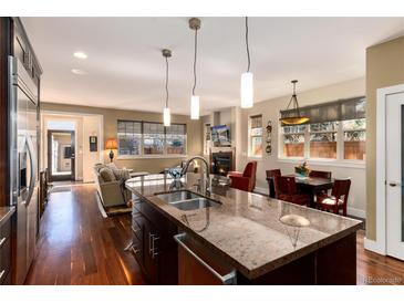 Modern kitchen with stainless steel appliances, granite countertops and an island, seamlessly connecting to an open living area at 2042 S Clayton St, Denver, CO 80210