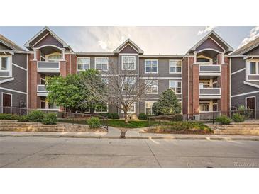 Condo's exterior with grey siding, brick accents, and landscaped grounds offers curb appeal at 14221 E 1St Dr # 303, Aurora, CO 80011