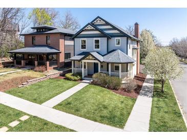 Charming two-story home with inviting front porch, manicured lawn, and beautiful landscaping at 3504 Newton St, Denver, CO 80211