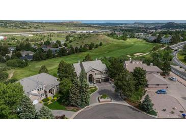 Stunning aerial view of a luxurious home on a lush golf course with mature trees and a circular driveway at 171 October Pl, Castle Rock, CO 80104
