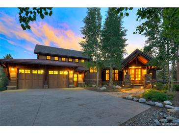 Inviting front exterior showcasing a three-car garage and charming architectural details at sunset at 805 Highfield Trl, Breckenridge, CO 80424
