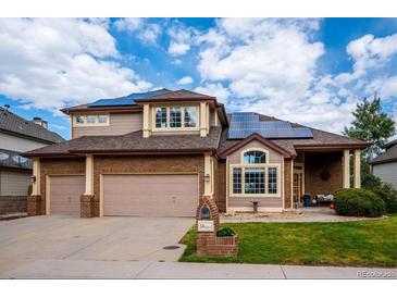 Attractive two-story home featuring a two-car garage, brick accents, lush lawn, and solar panels at 58 Rogers Ct, Golden, CO 80401