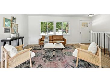 Bright living room featuring stylish decor, a brown leather couch, and two comfortable accent chairs at 1380 Holly E Dr, Broomfield, CO 80020