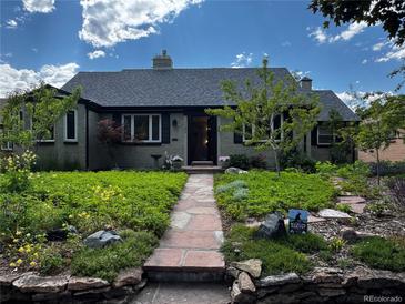 Charming single-story home featuring a stone walkway and a beautifully landscaped front yard with lush greenery and flowers at 1185 Glencoe St, Denver, CO 80220