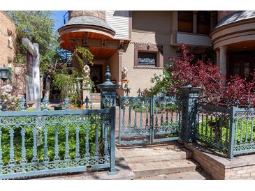Charming home with a blue iron gate, landscaped garden, and a turret-style covered entryway at 1022 N Pearl St # 101, Denver, CO 80203
