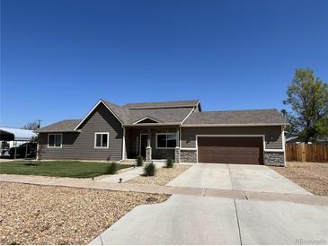 Charming single-Gathering home with a well-manicured lawn, concrete driveway, and stone facade accents at 504 Elizabeth Ave, Platteville, CO 80651