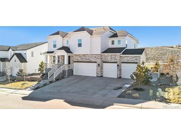 Inviting two-story home with a three-car garage, stone accents, and manicured landscaping at 5381 Hickory Oaks Trl, Castle Rock, CO 80104