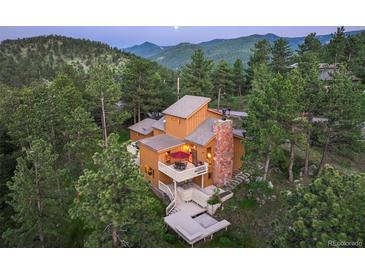 Stunning mountain home featuring multi-tiered decks and an elegant stone chimney surrounded by lush evergreen trees at 207 Kelly E Rd, Boulder, CO 80302